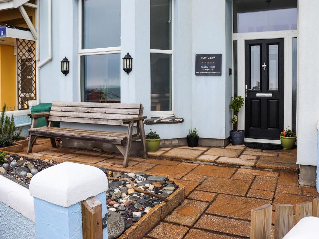 a wooden bench sitting outside of a house at Bay View - Uk52077 in Criccieth