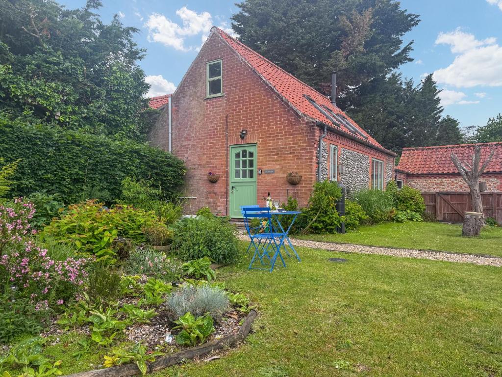 a brick house with a blue door in a garden at The Other House in Briston