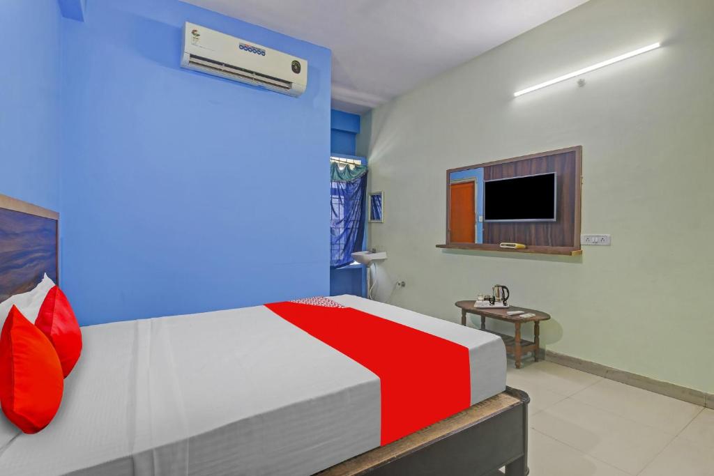 a bedroom with a bed and a tv on the wall at Hotel O Satya Inn in Karīmnagar