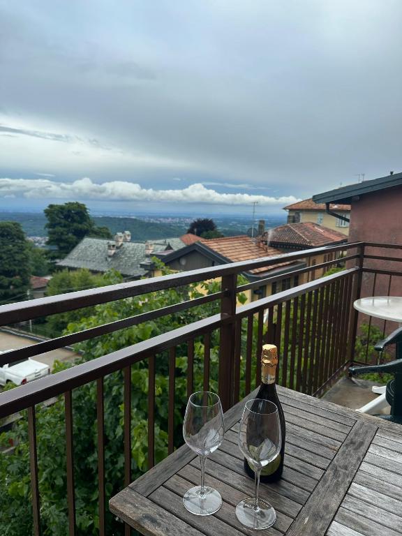 a bottle of wine and two glasses on a wooden table at Appartamenti Monti Como Lake in Brunate