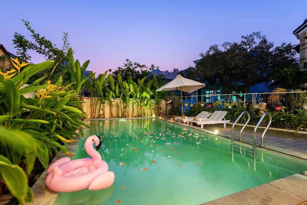 a swimming pool with a pink flamingo in the water at Flamingo Villa Hoi An in Hoi An