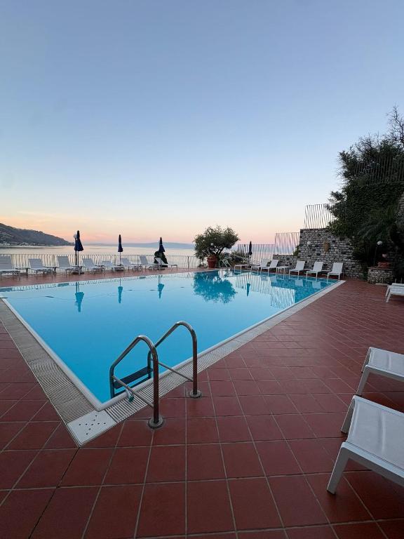 a swimming pool with chairs and people in the background at Bay Palace Mazzarò in Taormina