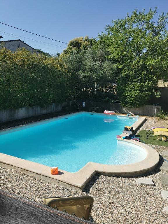 a large blue swimming pool with chairs and trees at Gite avec piscine in Crespian