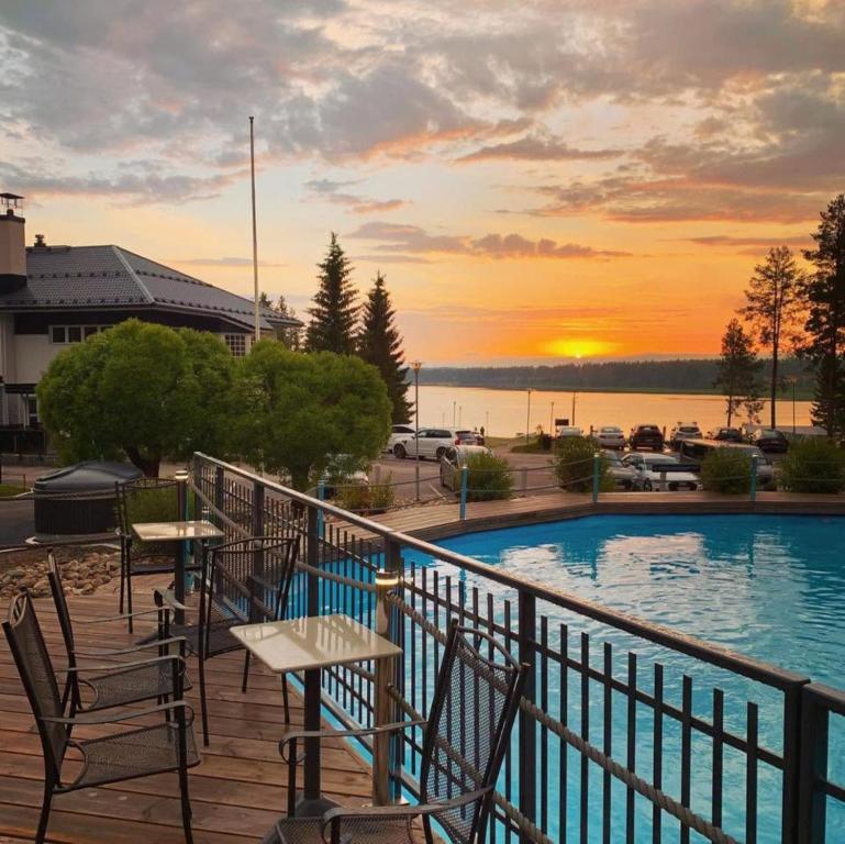 a balcony with tables and chairs next to a swimming pool at Hotel Aateli Lakeside in Vuokatti