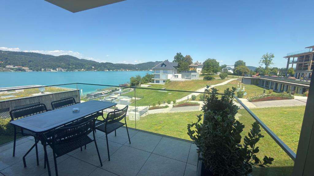 a balcony with a table and chairs and a view of the water at Hermitage Apartment E03B - Seeblick & Zugang in Maria Wörth