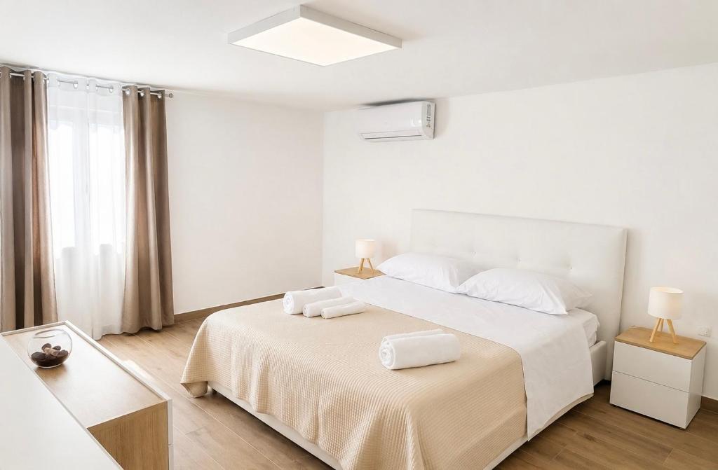 a white bedroom with a bed and a window at Palazzo Solera Rooms in Casarano
