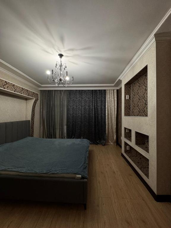 a bedroom with a bed and a chandelier at 3 комнатные апартаменты in Karagandy
