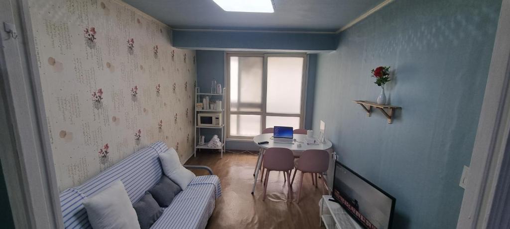 a living room with a couch and a table with a laptop at Liz House in Incheon