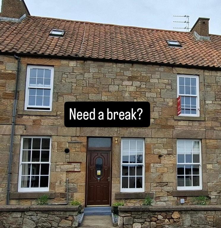 a brick house with a sign that reads need a break at Sailor's Rest in Anstruther