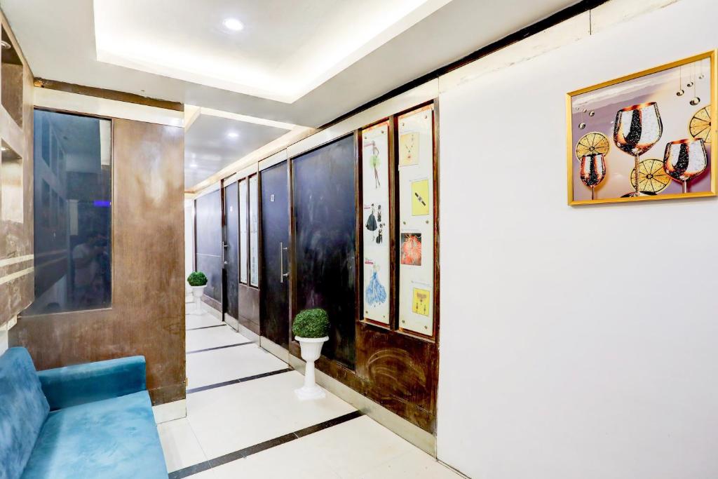 a hallway with a blue couch and paintings on the wall at Hotel O Kashish Residency in New Delhi
