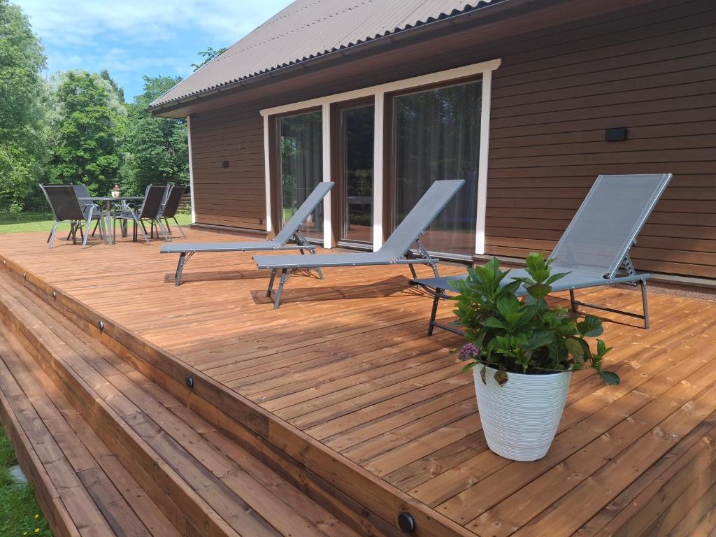 a wooden deck with chairs and a table on it at Riverside Sauna House in Savala