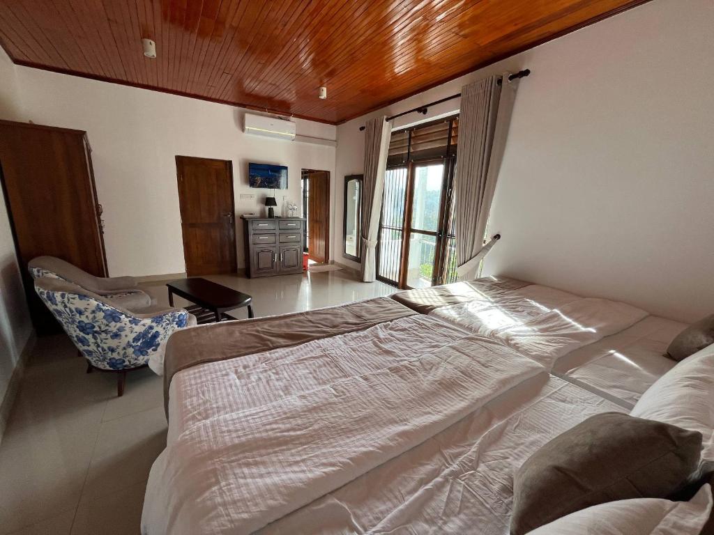 a bedroom with a large bed and a chair at Oli Villa in Belihuloya