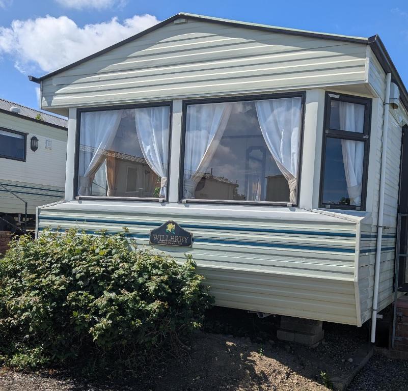 a white caravan with a window and a bush at Caravan 68 The Vale in Fishguard