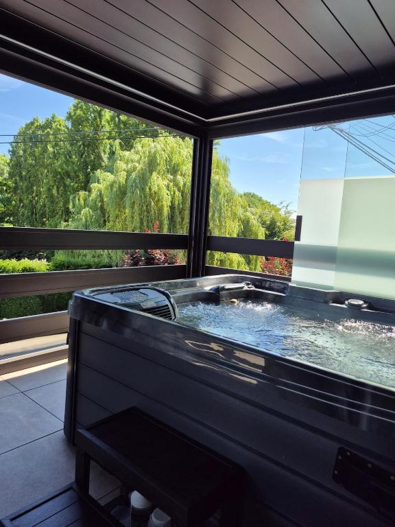 a jacuzzi tub in a room with a window at Maison H - Logement de luxe avec jacuzzi privé et home cinéma immersif in Herstal