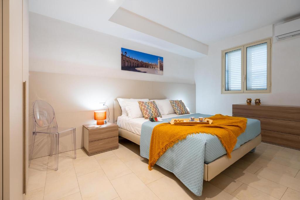 a bedroom with a bed and a chair and windows at LOGGIATO HOUSE-Ispica in Ispica