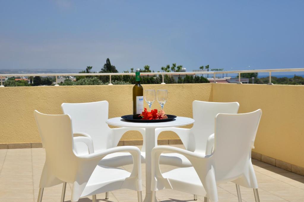 a table with white chairs and wine glasses on a balcony at Makronisos Village in Ayia Napa