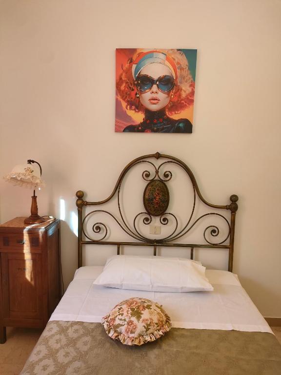 a bed with a headboard and a painting on the wall at I Tre Archi in Suvereto