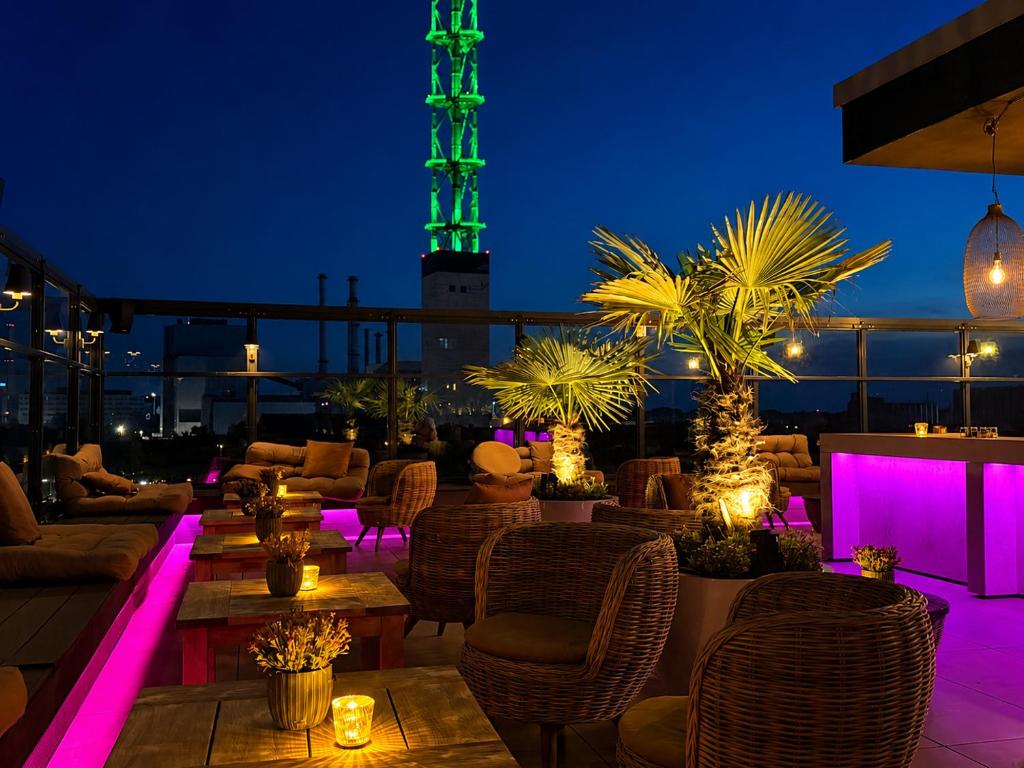 a rooftop patio with tables and chairs at night at Twins Hotel in Duisburg
