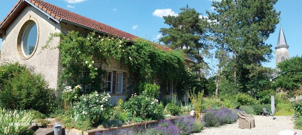 a house with a garden and a church at Gîte La Cour Cachée in Saulx-en-Woëvre
