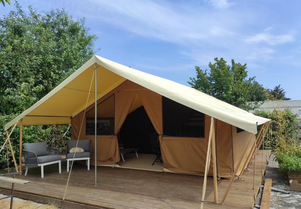 a tent with two chairs on a wooden deck at clos du loguy in Pénestin