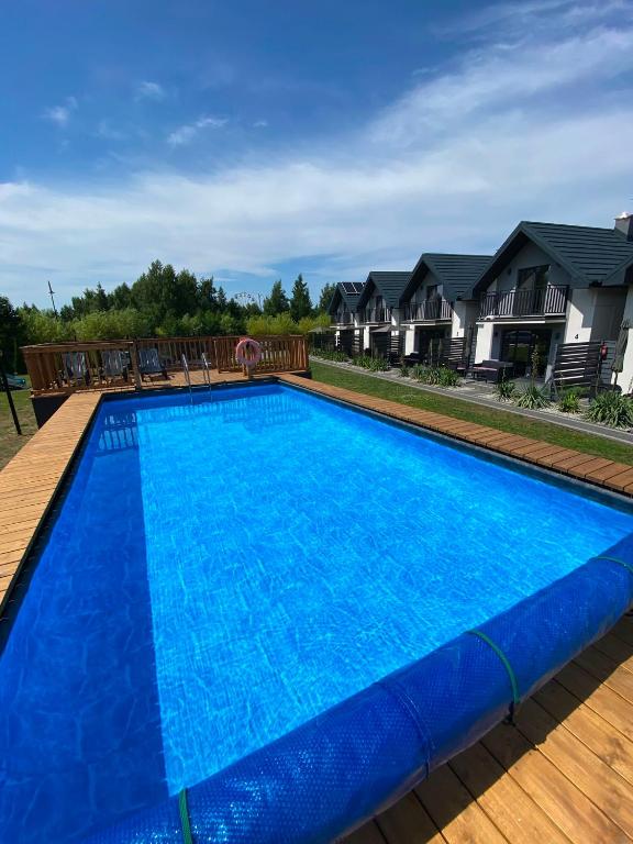 a large blue swimming pool with chairs and houses at Antracytowy Zakątek in Łeba