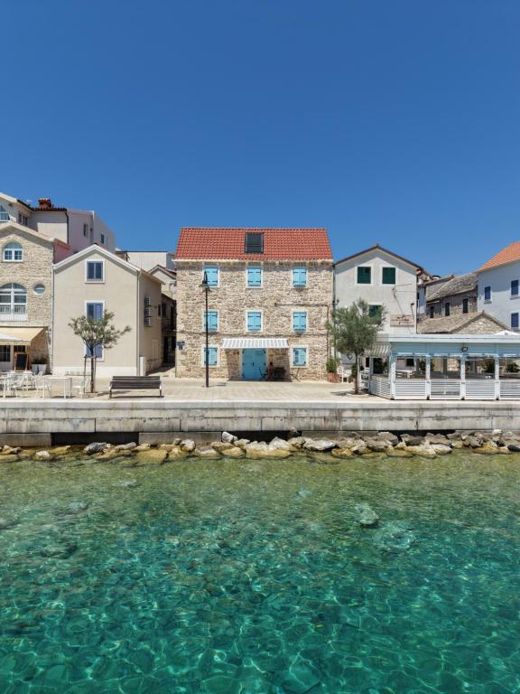 a house on the water in front of some buildings at Apartment Dane in Primošten
