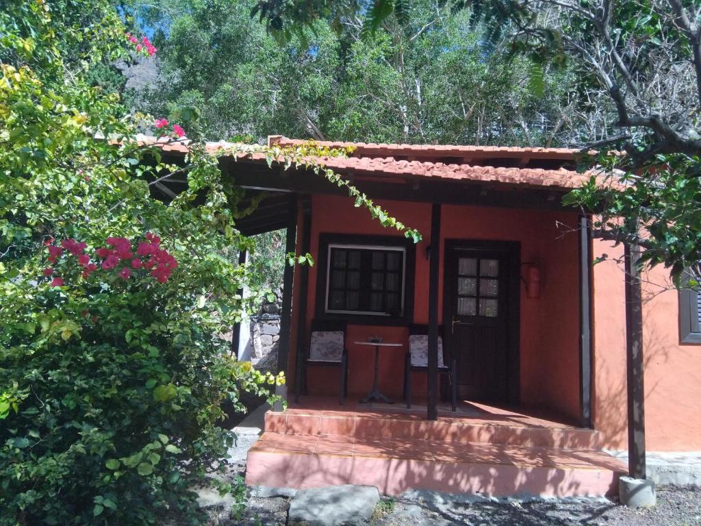 a small red building with a door and some flowers at Finca Nim 2 in Mogán