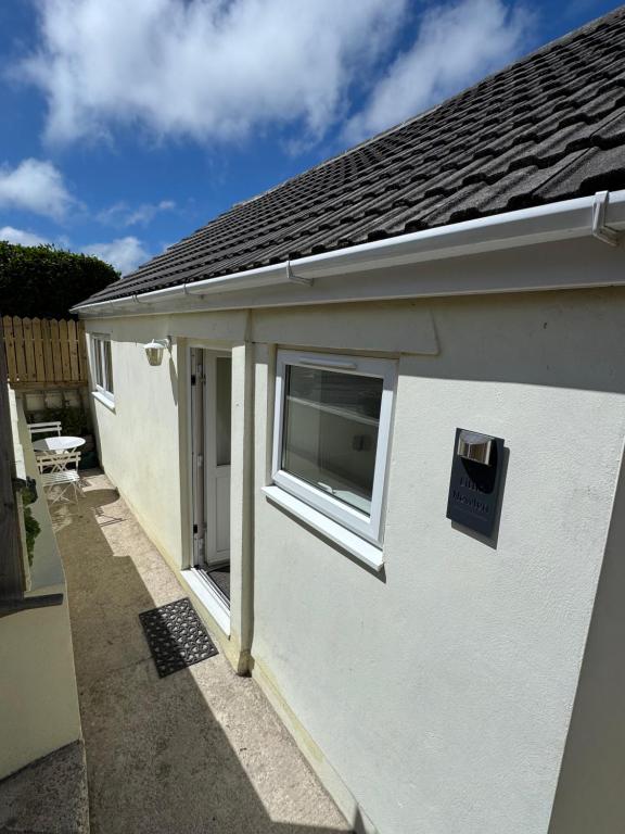 a white house with a window and a sign on it at Little Newlyn in Newlyn