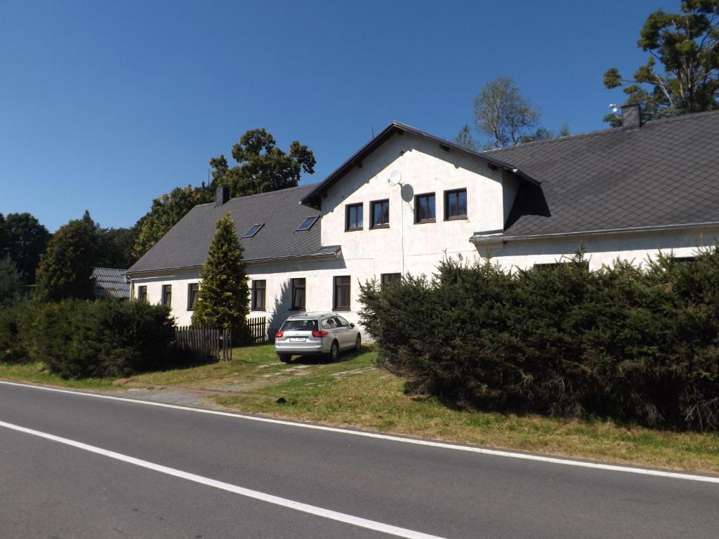 a white house with a car parked on the side of the road at Ubytování u Nováků in Malá Morávka