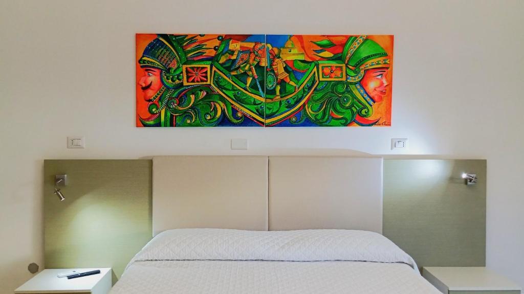 a painting hanging above a bed in a bedroom at Medoro Camere Milazzo in Milazzo