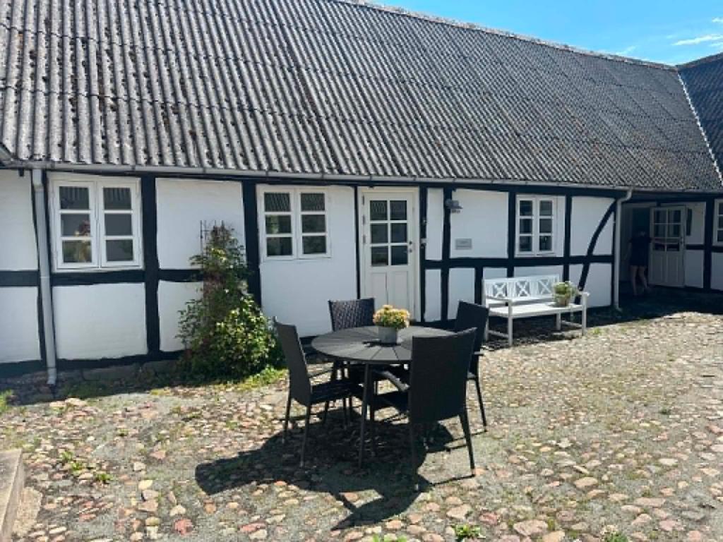 ein weiß-schwarzes Haus mit einem Tisch und Stühlen in der Unterkunft Tøndegården 3 rooms apartment in Odense