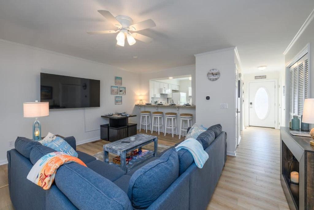 a living room with a blue couch and a kitchen at Bethany Beach Retreat with Pool - VTC in Frankford
