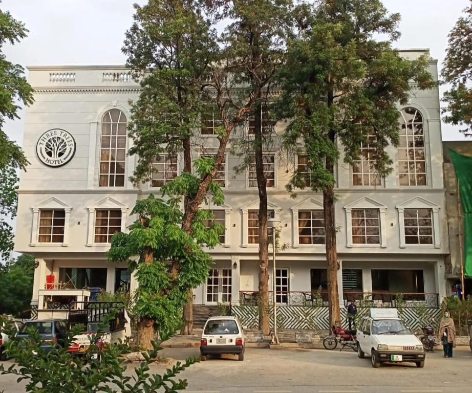 ein weißes Gebäude, vor dem Autos parken in der Unterkunft Taj Signature Boutique Hotel Islamabad by LMY Hospitality in Islamabad