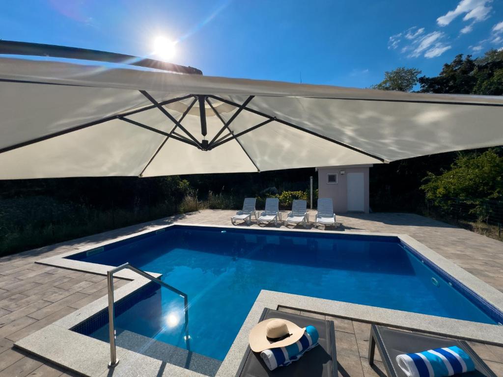 a swimming pool with a large white umbrella at Holiday Home Slap Koćuša in Ljubuški