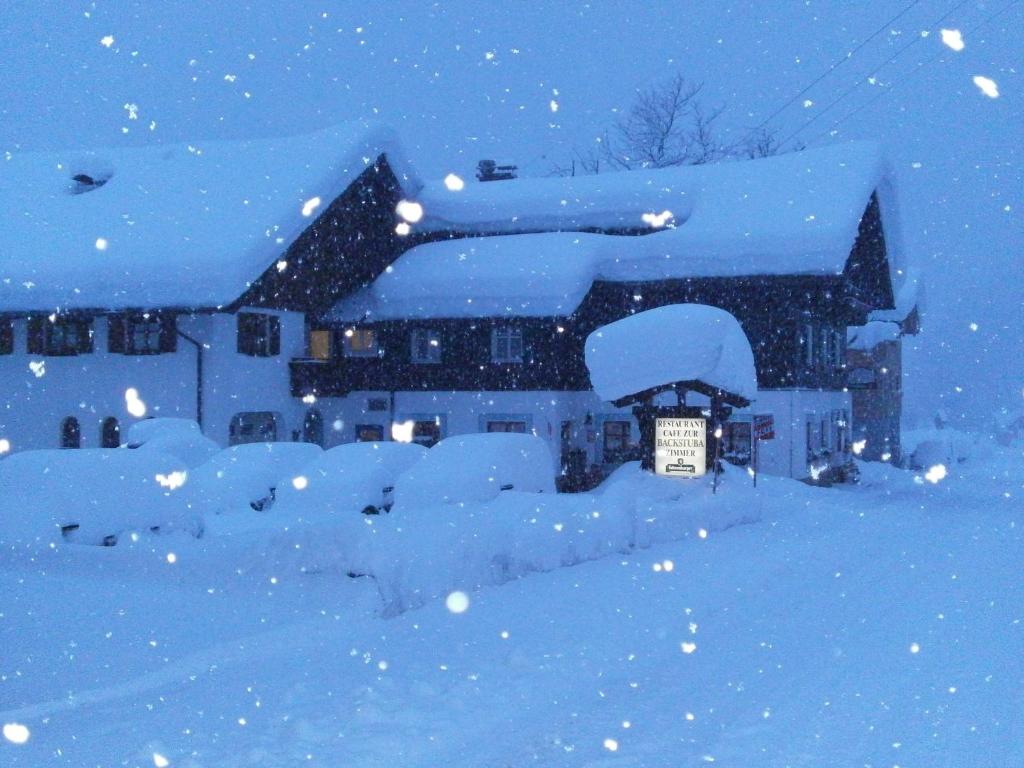 una casa cubierta de nieve por la noche en Pension Backstuba en Partenen