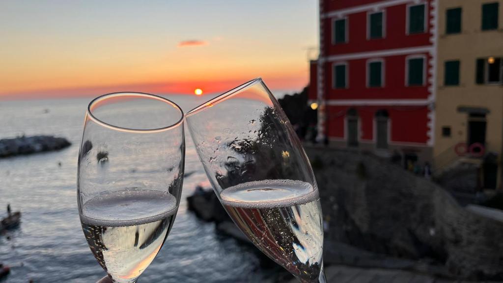 two glasses of wine sitting next to the ocean at Giovanna dei Rocca - appartamento sul mare in Riomaggiore