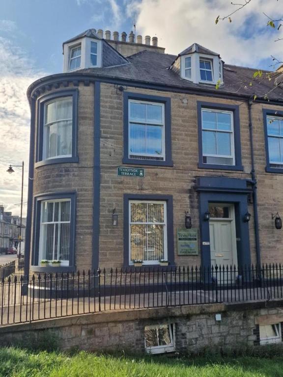 a brick house with a fence in front of it at Teviotside Travel Inn in Hawick