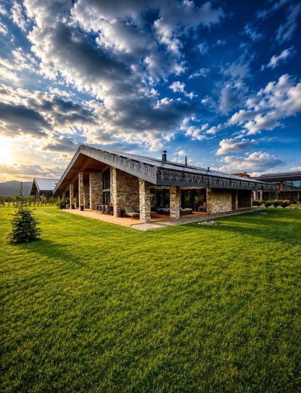a building with a grass field in front of it at Hypnotic Thermal Villas with private SPA in Banya