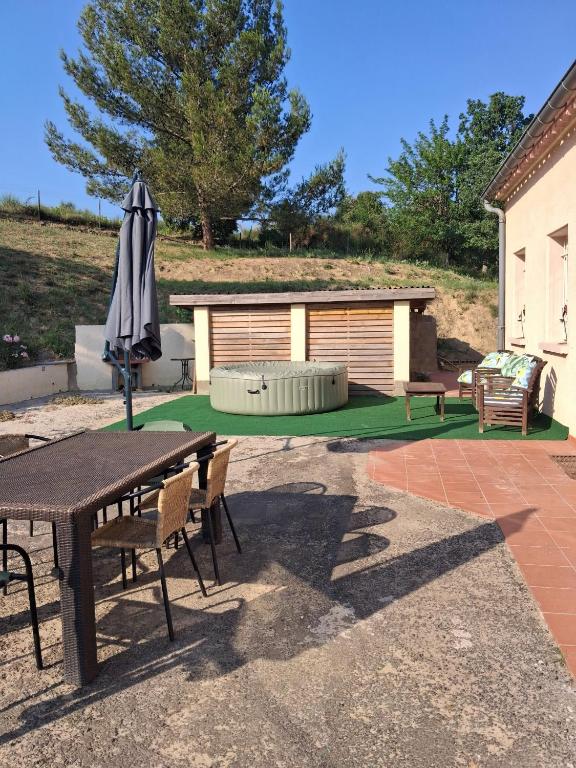 a patio with an umbrella and a table and chairs at Maison Sol Air in Montazels