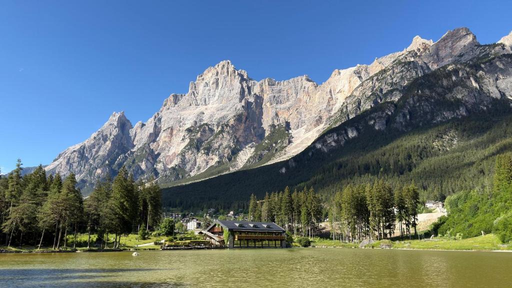 a house on a lake in front of a mountain at Chalet Al Lago in San Vito di Cadore