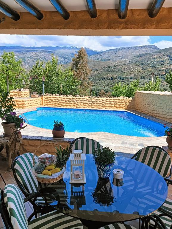 a patio with a table and chairs and a swimming pool at Casas Amaro in Órgiva