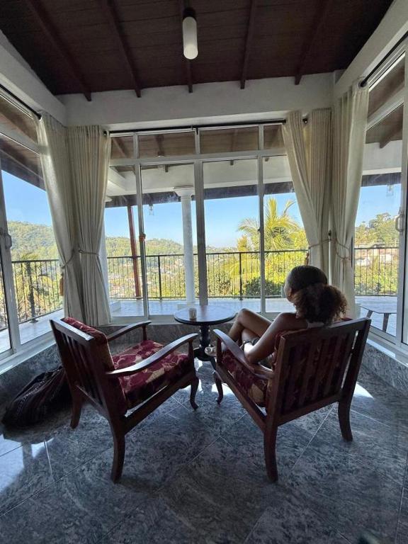 a woman sitting on a couch in a room with windows at Kandyan View Homestay - Foreign in Kandy