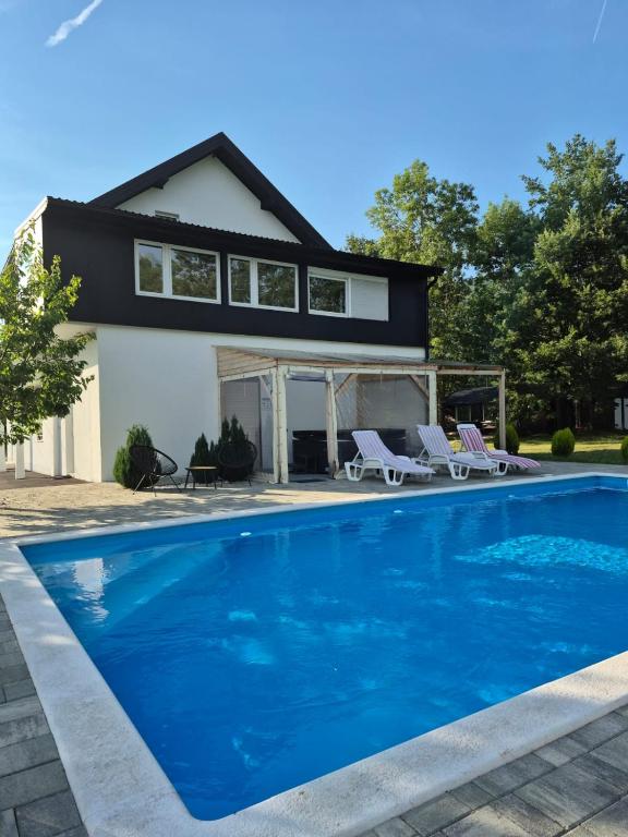 a house with a blue swimming pool in front of a house at Lika Relax and Party House with sauna, jacuzzi and outdoor heated swimming pool in Lovinac