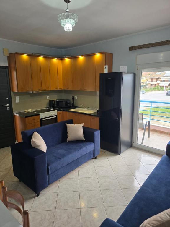 a living room with a blue couch and a refrigerator at KSD apartment in Kallithea Halkidikis