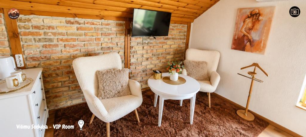 a room with two chairs and a table and a tv at Vilimu Sodyba - VIP Room in Kriukai