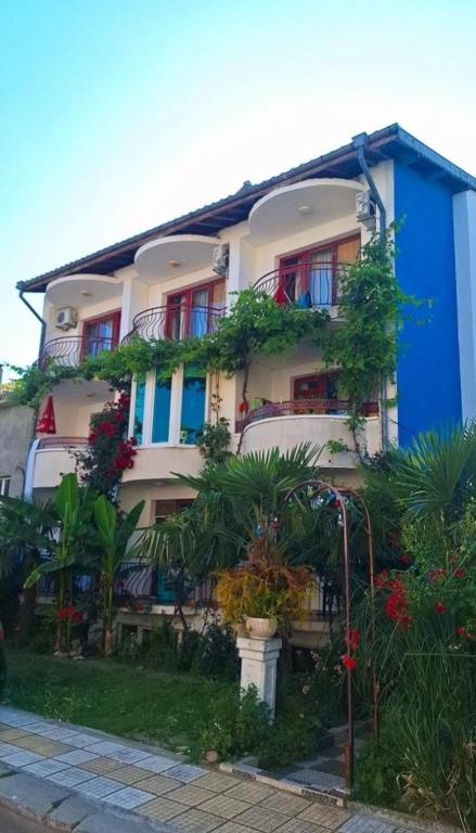 a blue and white building with plants in front of it at Къща за Гости Тера in Kiten