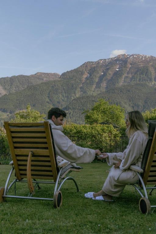 a man and woman sitting on chairs in the grass at Hotel Metzgerwirt in Sankt Veit im Pongau