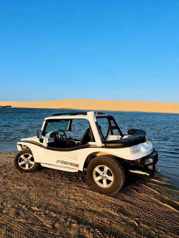 a white jeep parked on a beach near the water at Brisa do Preá- 700m da Praia do Preá -12km de Jeri in Prea