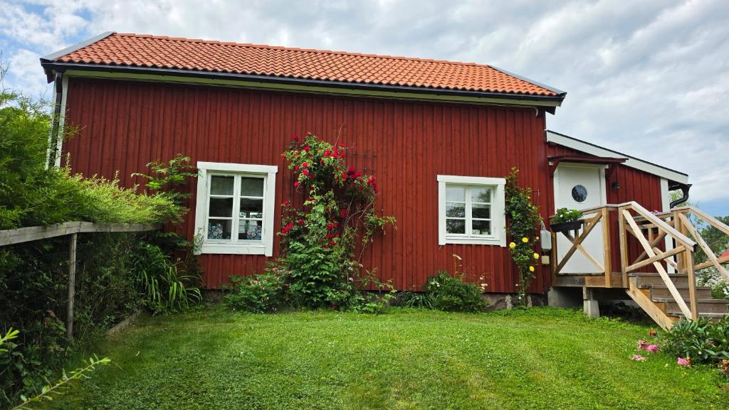 a red house with white windows and a yard at Kolmårdstorpet Blomsätter in Kolmården
