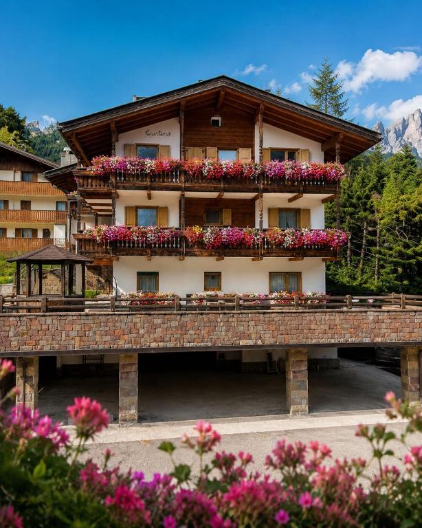 ein Gebäude mit Blumen auf dem Balkon in der Unterkunft Hotel Ai Pini in Vigo di Fassa